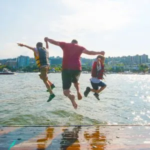 Three people mid-jump into the Willamette River