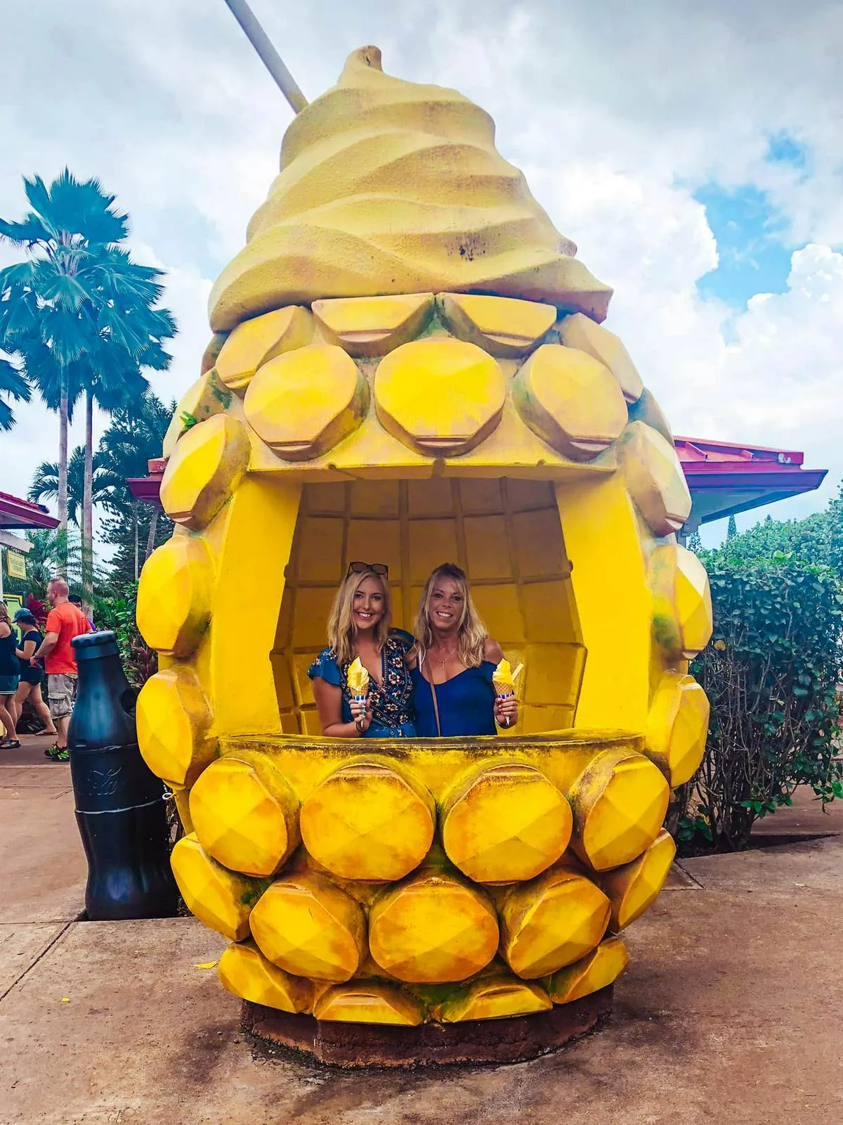 Tourists posing with Dole Whip at the giant pineapple sign at Dole Plantation