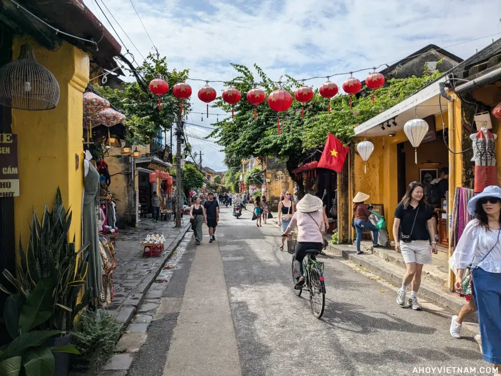 Tourists walking down a small street in Old Town Hoi An.