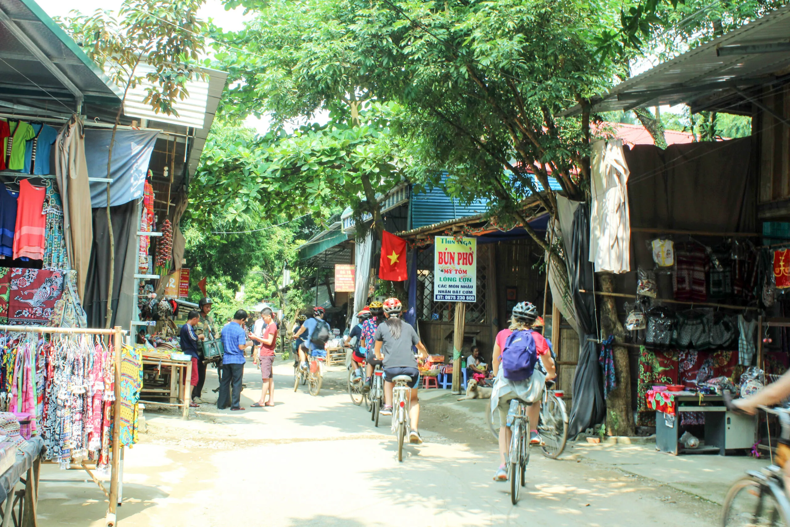 Traveler cycling through a rural village path surrounded by greenery