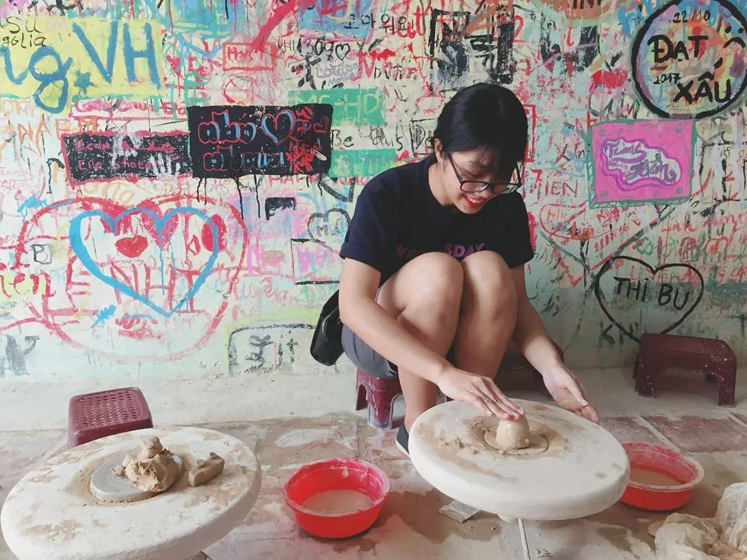 Travelers attempting to make pottery on a traditional hand-turned wheel in Bat Trang