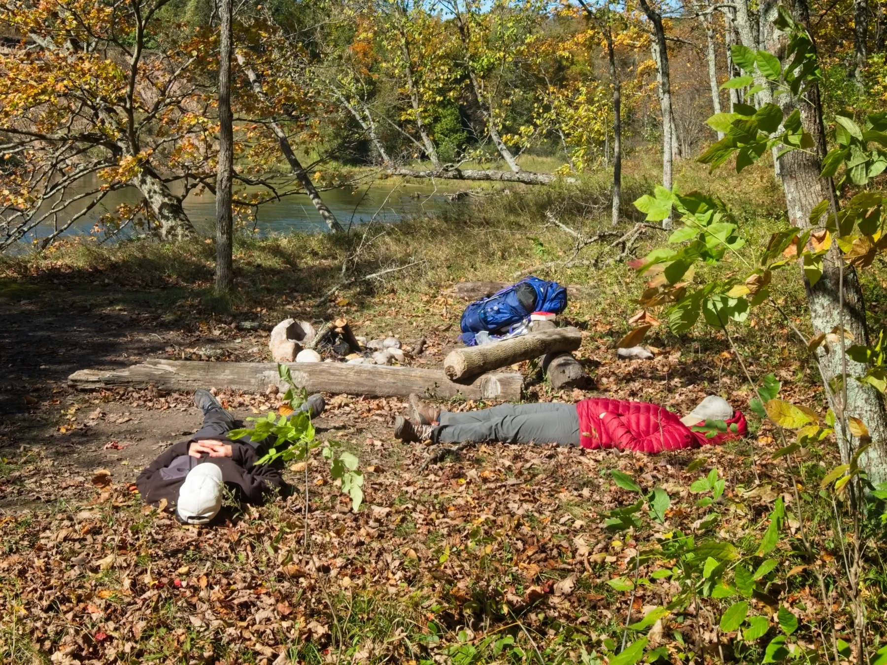 Two backpackers taking a break and napping beside the Manistee River