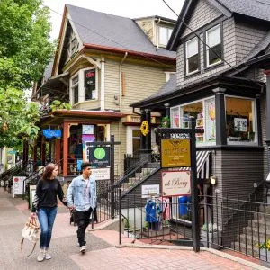 Two people walking past boutique shops housed in Victorian homes in Northwest Portland