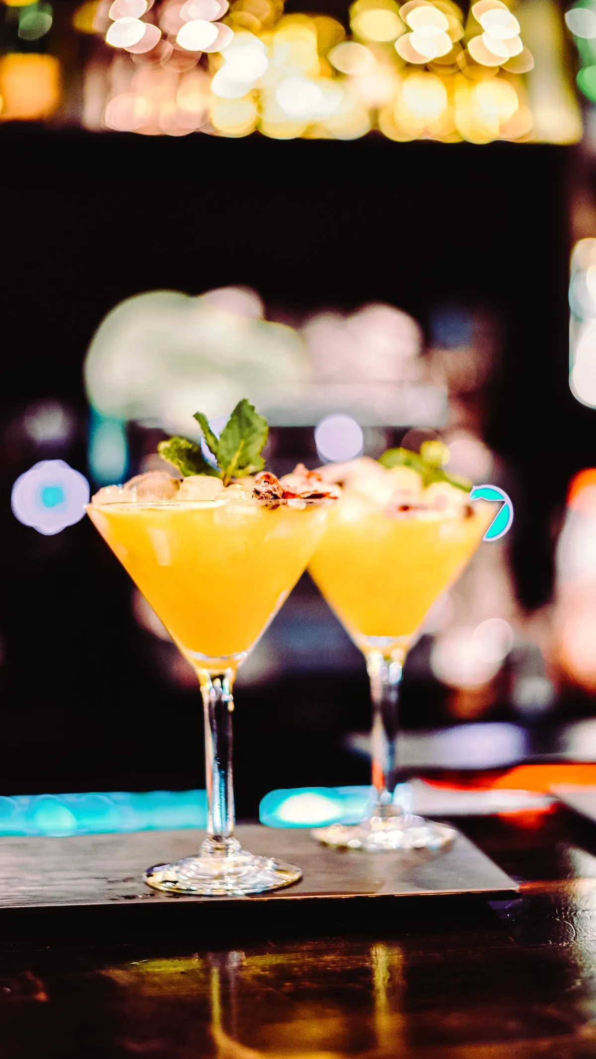 Two yellow cocktails on a bar, representing the diverse drink options when going out in Manhattan