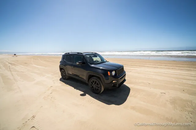 Vehicles driving on a sandy beach near the ocean