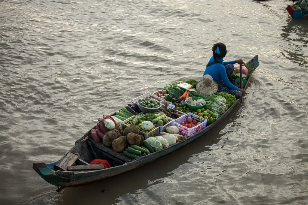 Vendor in a small boat selling fresh produce at a floating market in Vietnam’s Mekong Delta