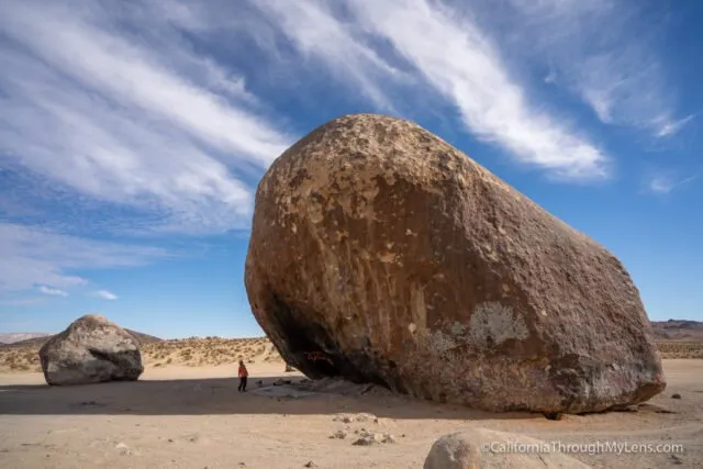 Very large freestanding boulder in a flat desert landscape