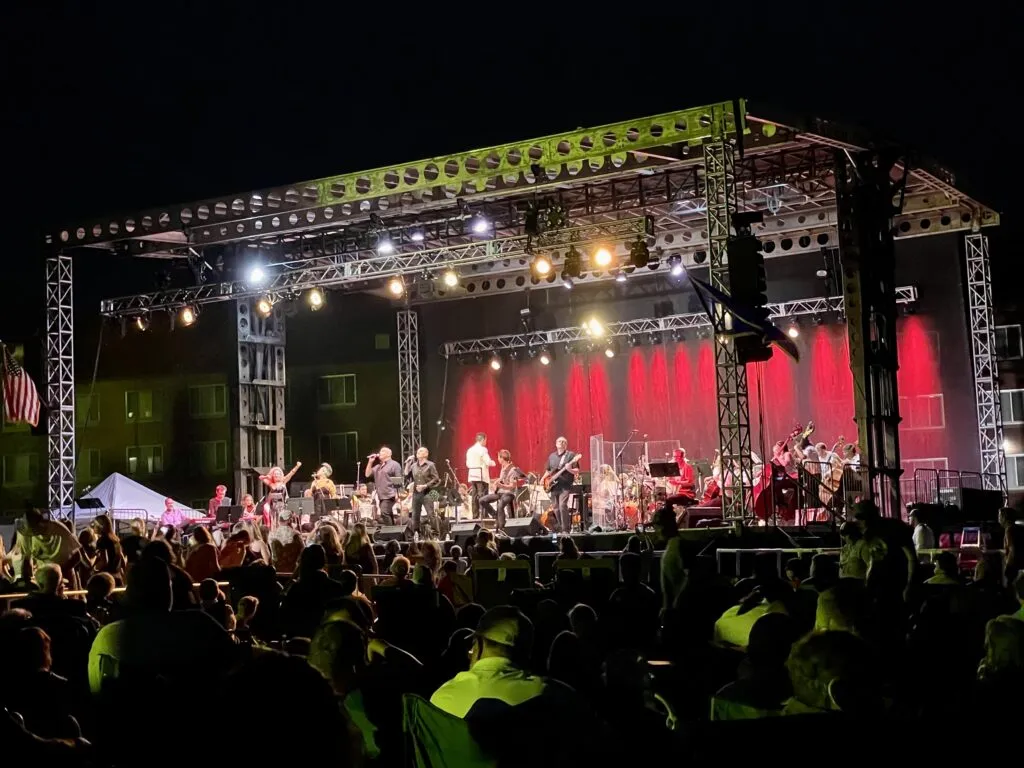 View of an outdoor symphony orchestra performance with a mountain backdrop in Helena, Montana