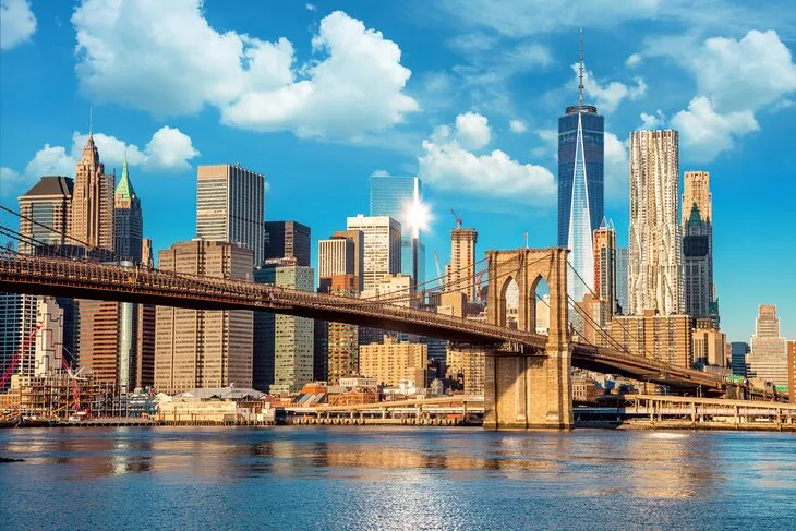View of Brooklyn Bridge and iconic New York City skyline at sunset, one of new york most famous places.