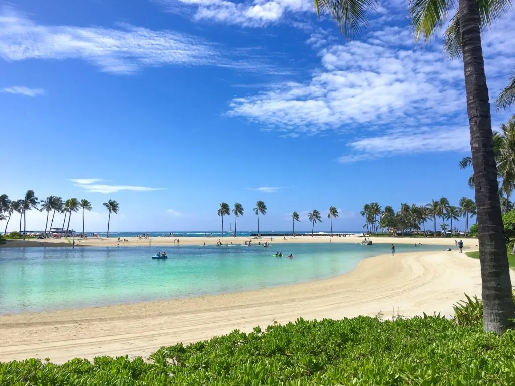 View showing the mild waves and sandy shoreline of Duke’s Beach in Honolulu, perfect for a relaxing swim