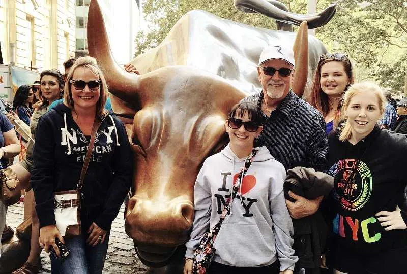 Visitors posing with the iconic Charging Bull statue in the Financial District, NYC
