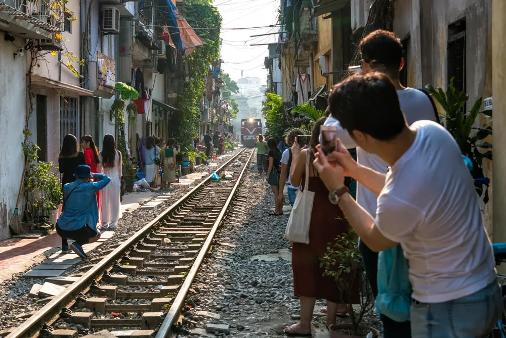 Visitors stand close to the tracks as a train passes by Hanoi Train Street, a thrilling urban experience
