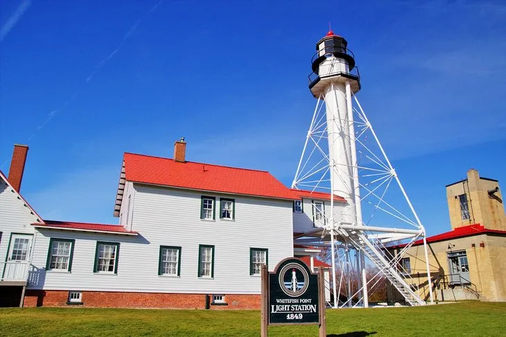 Whitefish Point Light Tower next to the Great Lakes Shipwreck Museum buildings