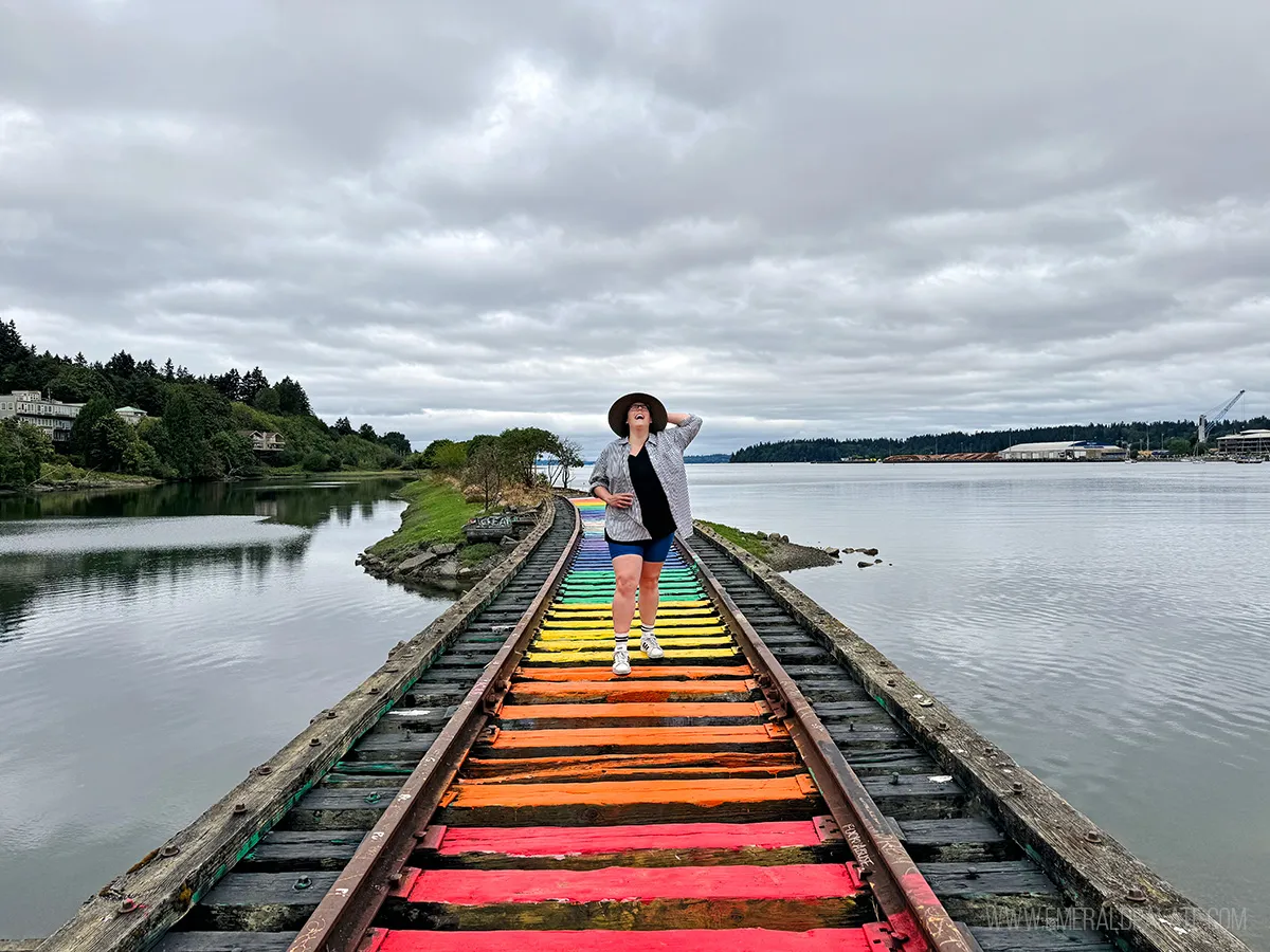 Woman laughing while walking along railroad tracks painted in rainbow colors