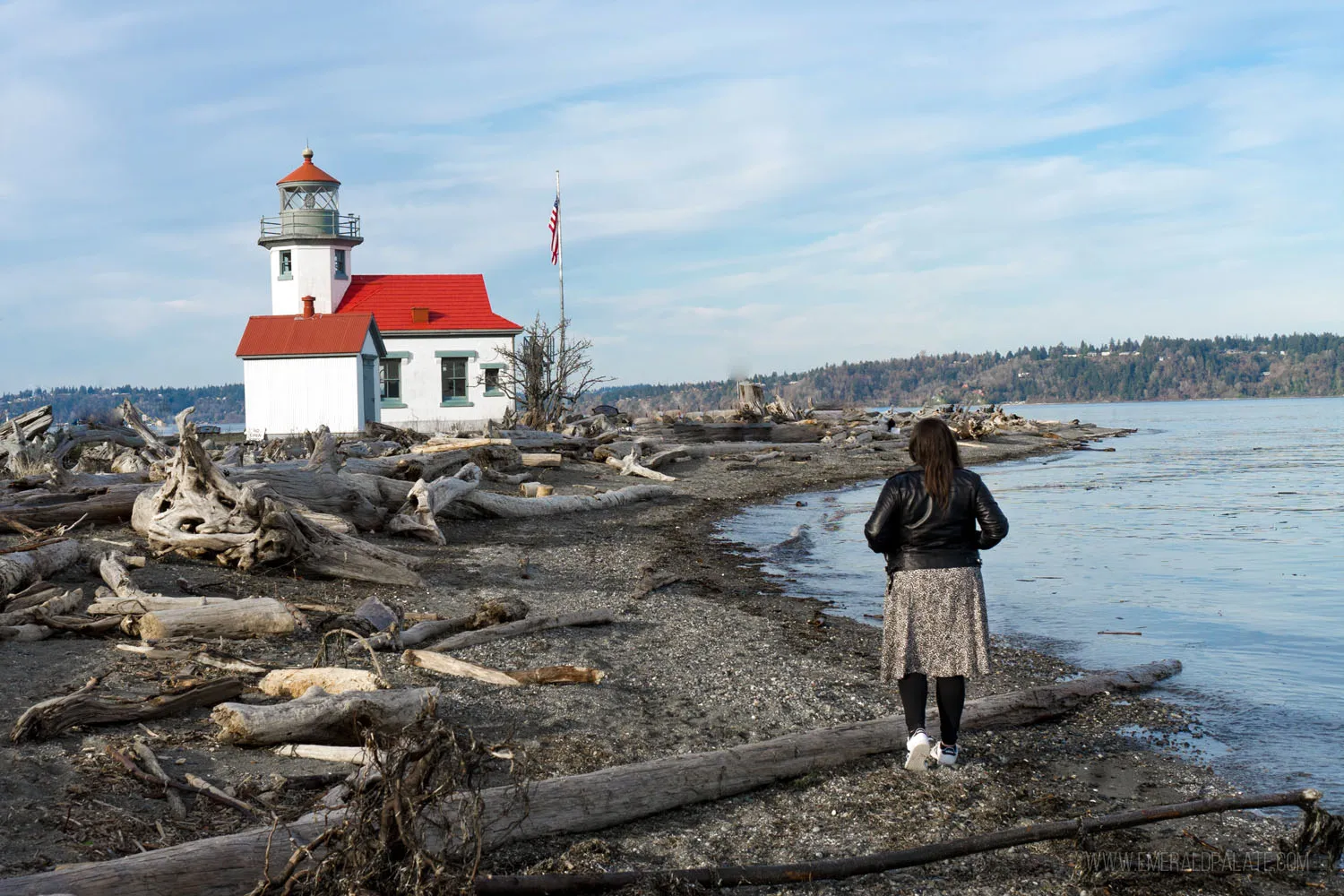 Woman on a beach with the Point Robinson Lighthouse on Vashon Island