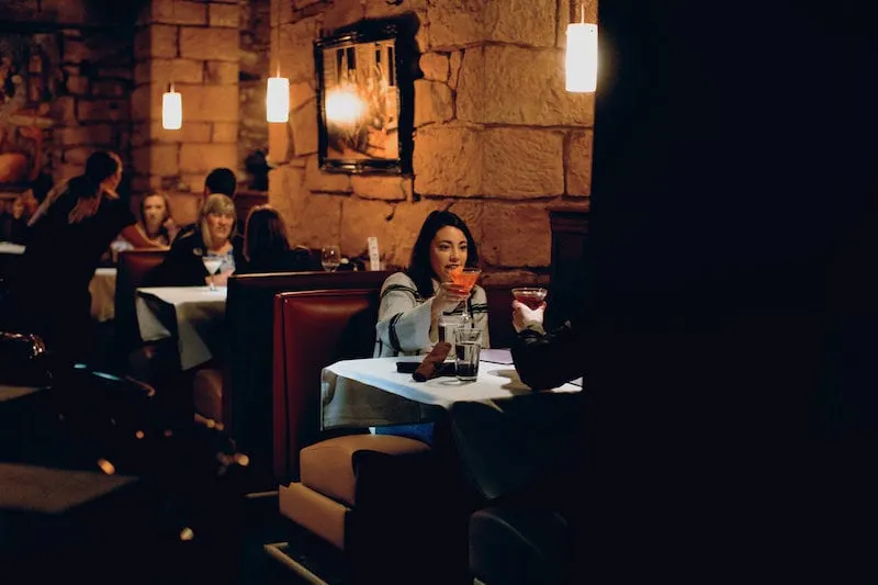 Woman raises a cocktail at the Rabbit Hole in Colorado Springs, one of the best restaurants in Colorado Springs