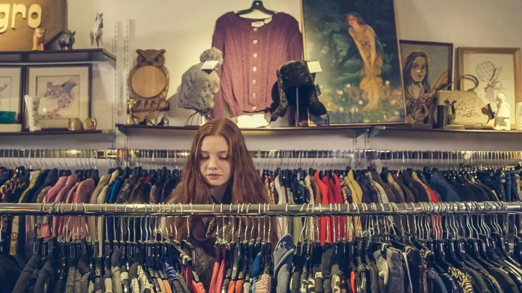 Woman searching through clothing racks at a vintage or thrift shop in NYC