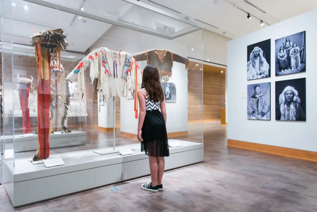 Woman viewing exhibits of Native American clothing and photos at The Brinton Museum - Cultural Things To See And Do In Wyoming